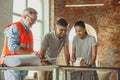 Foreman or achitect shows house, office or store design plans to a young couple