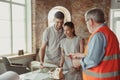 Foreman or achitect shows house, office or store design plans to a young couple