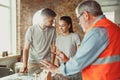 Foreman or achitect shows house, office or store design plans to a young couple