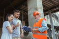 Foreman or achitect shows house, office or store design plans to a young couple