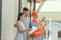 Foreman or achitect shows house, office or store design plans to a young couple