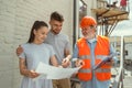 Foreman or achitect shows house, office or store design plans to a young couple