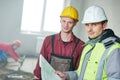 Foreman builder and construction worker with blueprint in indoor apartment Royalty Free Stock Photo