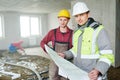 Foreman builder and construction worker with blueprint in indoor apartment Royalty Free Stock Photo