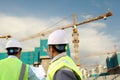 Foreman construction discussing at the site pointing at the crane in the background