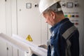 Foreman electrician examines the working draft next to the dashboard. Energy and electrical safety