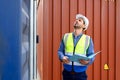 Foreman or Engineer wears white helmet and reflection shirt to control or check inventory details of containers box. Container Royalty Free Stock Photo