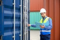 Foreman or Engineer wears white helmet and reflection shirt to control or check inventory details of containers box. Container Royalty Free Stock Photo