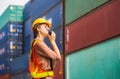 Foreman in hardhat and safety vest holding clipboard checklist and talks on two-way radio control loading containers box from