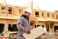 Foreman holding architecture drawing plan on paper at construction site. Royalty Free Stock Photo
