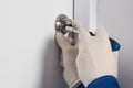 Foreman`s hands repairing a lock on a white front door, close-up Royalty Free Stock Photo