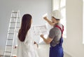 Foreman showing to a homeowner woman blueprint with design project of her new apartment. Royalty Free Stock Photo