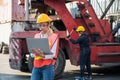 Foreman woman and worker man operate checking the forklift container cargo harbor holding laptop computer