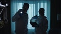 Forensic experts man and woman use a flashlight tablet in work at a crime scene in a dark apartment. A team of forensic