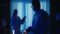 Forensic experts man and woman use a flashlight tablet in work at a crime scene in a dark apartment. A team of forensic