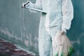 Forensic investigator collecting evidence on a murder scene on a street holding a plastic bag and wearing a hazmat suit