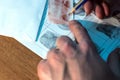 The forensic reader compares fingerprints. Close-up of male hands with a pencil.