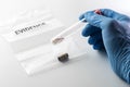 Forensic scientist`s hand holding glass tube over evidence bag with bullet case