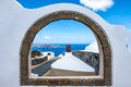 Foreshortening of Santorini island from a window in an arch
