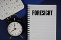 Foresight text written on notepad with calculator and alarm clock on navy blue background Royalty Free Stock Photo