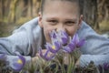 In the forest  boy lies on the ground and hugs the flowers to pasque-flower Royalty Free Stock Photo