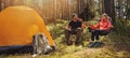 Forest camping - young hiker couple enjoying cup of tee at campsite