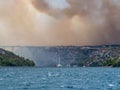 Forest fire in Croatia, summer natural disaster close to national park Krka, Sibenik region, boats and yachts escaping Skradin to