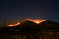 Forest Fire at night. Huge fire on mountain. View of trees and grass burning in forest fire. Wildfire fueled by strong winds force