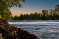The waterfall on the river is illuminated by the rays of the soft sunset sun. Royalty Free Stock Photo