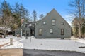 Forest house with grey exterior in a snow-covered surrounding captured from the front in winter