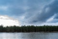 Forest lake with ice remnants, trees on the shore and dark rainy clouds in the sky. Wildlife spring landscape on cloudy evening Royalty Free Stock Photo