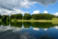 Beautiful forest landscape. White clouds are reflected in the forest lake. Royalty Free Stock Photo