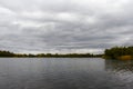 Forest lake under a cloudy sky in early autumn