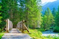 Forest landscape in Italian Alps with wooden bridge and river