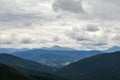 Forest, mountains and small Carpathian village in the valley under cloudy sky