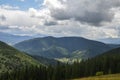 Forest, mountains and small Carpathian village in the valley under cloudy sky