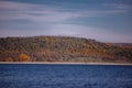 Forest reflected in the lake in autumn season. Beautiful landscape with colorful trees near the blue water Royalty Free Stock Photo