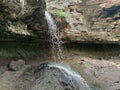 Forest waterfall of gray rocks. On the stones, green moss and lichens. Green grass. Saharna- Moldova.