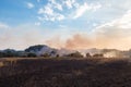 Forest wildfire. Burning field of dry grass and trees. Heavy smoke against blue sky. Wild fire due to hot windy weather Royalty Free Stock Photo