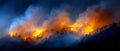 Forest wildfire burning trees on mountain hillside with flames and smoke representing natural disaster climate change Royalty Free Stock Photo