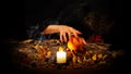 Forest witch making passes above burning candle and pumpkin on the altar in the dark. Female hands with long sharp nails Royalty Free Stock Photo