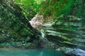 Forested cliffs covered with ivy and moss with waterfall flowing down