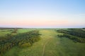 Forested flat terrain with winding dirt roads in the rays of the setting sun. Shooting from a drone