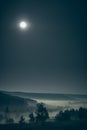 Forested hills in fog with the full moon in the starry sky at night time Royalty Free Stock Photo