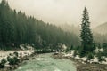 Forested mountain slope and river in low lying cloud