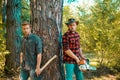 Foresters in the forest. Hipsters on serious face carries axe. Lumberjack brutal holds axe. Brutal lumberjack concept. Royalty Free Stock Photo