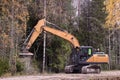 Forestry mulching machine attached to excavator, being used to clear roadside brush.