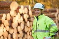 Forestry worker in protective workwear in front of wood lumber cut tree Royalty Free Stock Photo