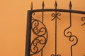 Forged beautiful vintage metal brown fence, fragment of a gate on the background of the wall