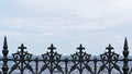 Forged black iron fence with decorative ornate pattern, blue sky background Royalty Free Stock Photo